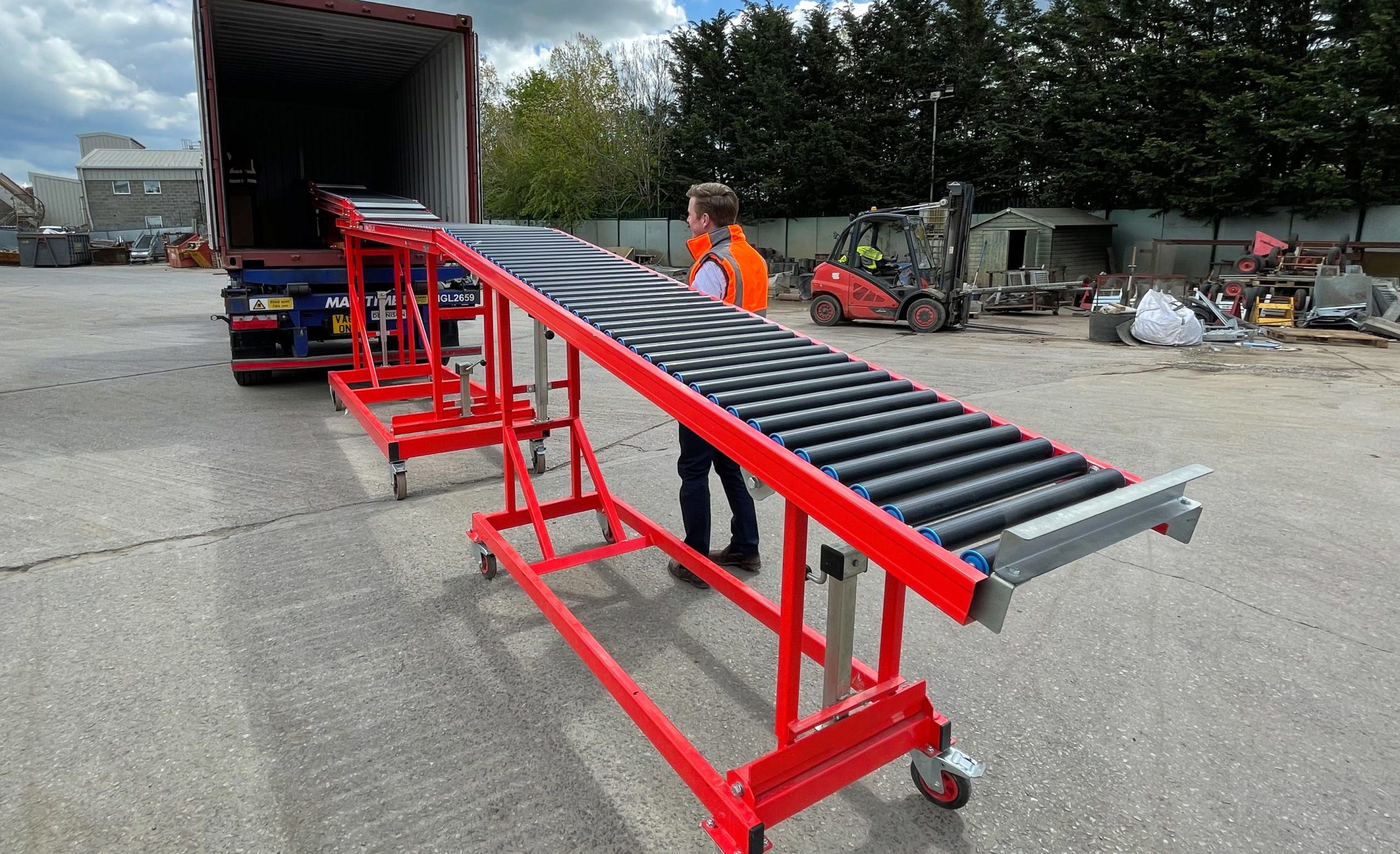 Operatore che utilizza un trasportatore telescopico a rulli folli per scaricare un container.